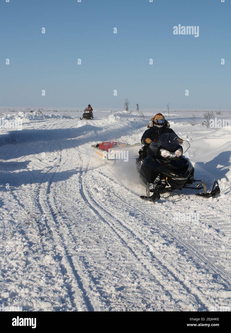 Due lavoratori in motoslitta durante la costruzione invernale dell'autostrada Inuvik-Tuktoyaktuk, territori del Nord-Ovest, l'Artico del Canada. Foto Stock