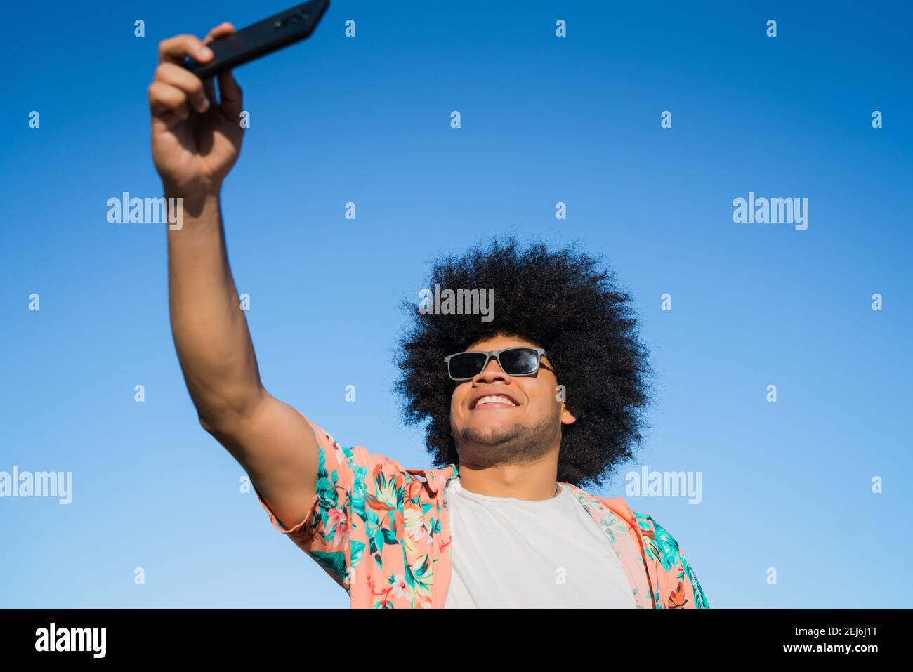 Uomo latino che prende un selfie con il telefono all'aperto. Foto Stock