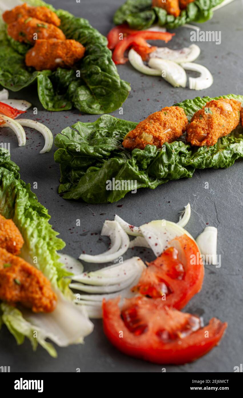 Piatto tradizionale turco a base di bulgaro e lenticchie conosciute come mercimek koftesi (pentola) servita su lattuga verde con cipolla e pomodoro a fette Foto Stock