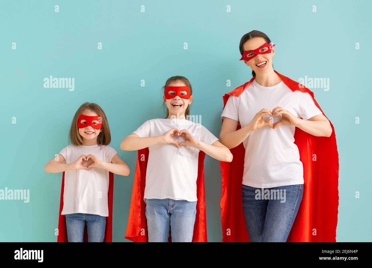 Madre e i suoi figli giocano insieme. Ragazze e mamma in costumi Superhero divertendosi e sorridendo. Vacanza in famiglia e insieme. Foto Stock