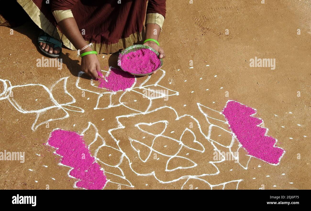 Donna indiana disegnando rangoli di fronte a casa o tempio durante il festival di raccolta, pongal o makar sankranti Foto Stock