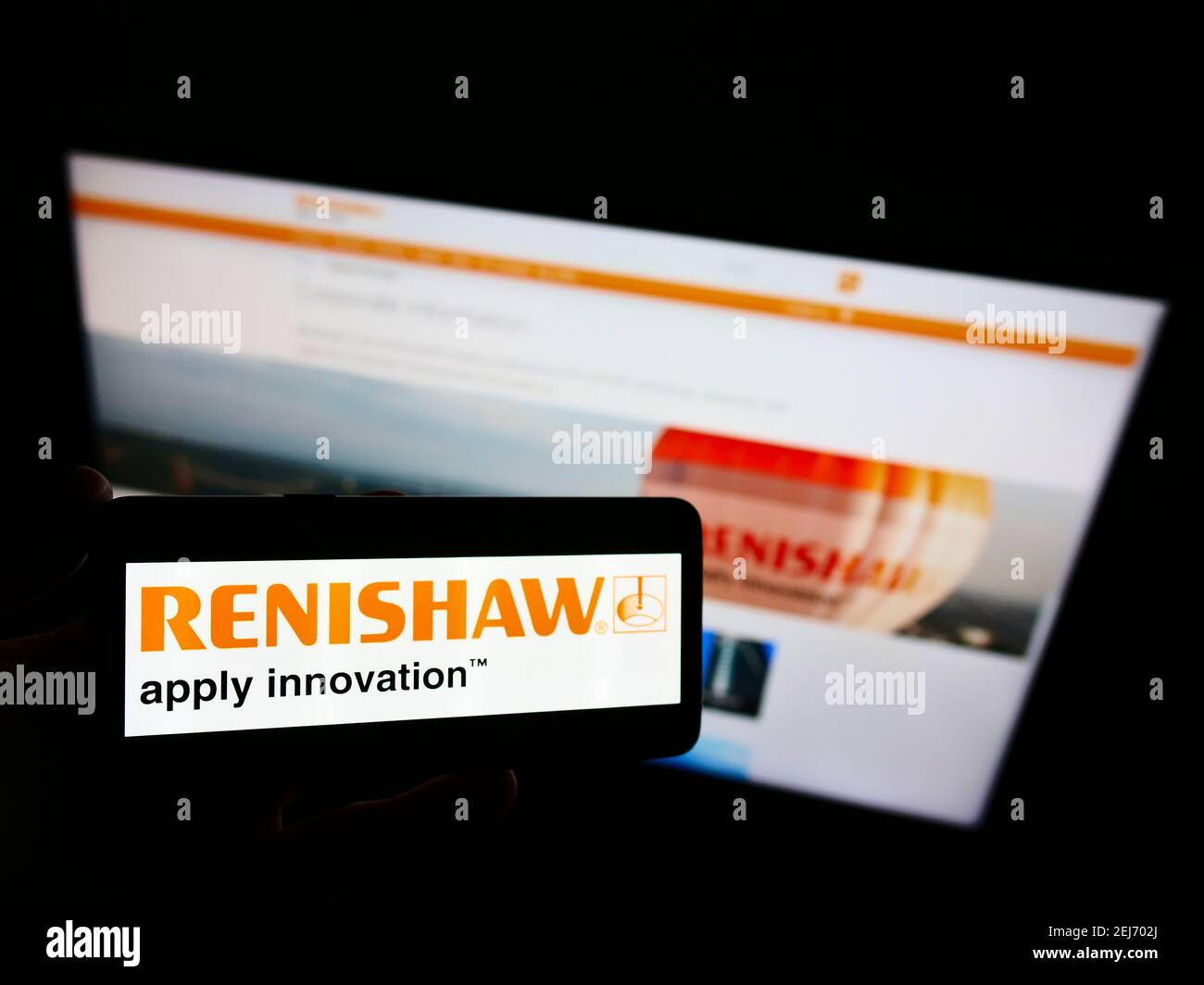 Vista ad alto angolo di una persona che tiene uno smartphone con il logo della società di ingegneria britannica Renishaw plc sullo schermo con pagina web. Mettere a fuoco il display del telefono. Foto Stock