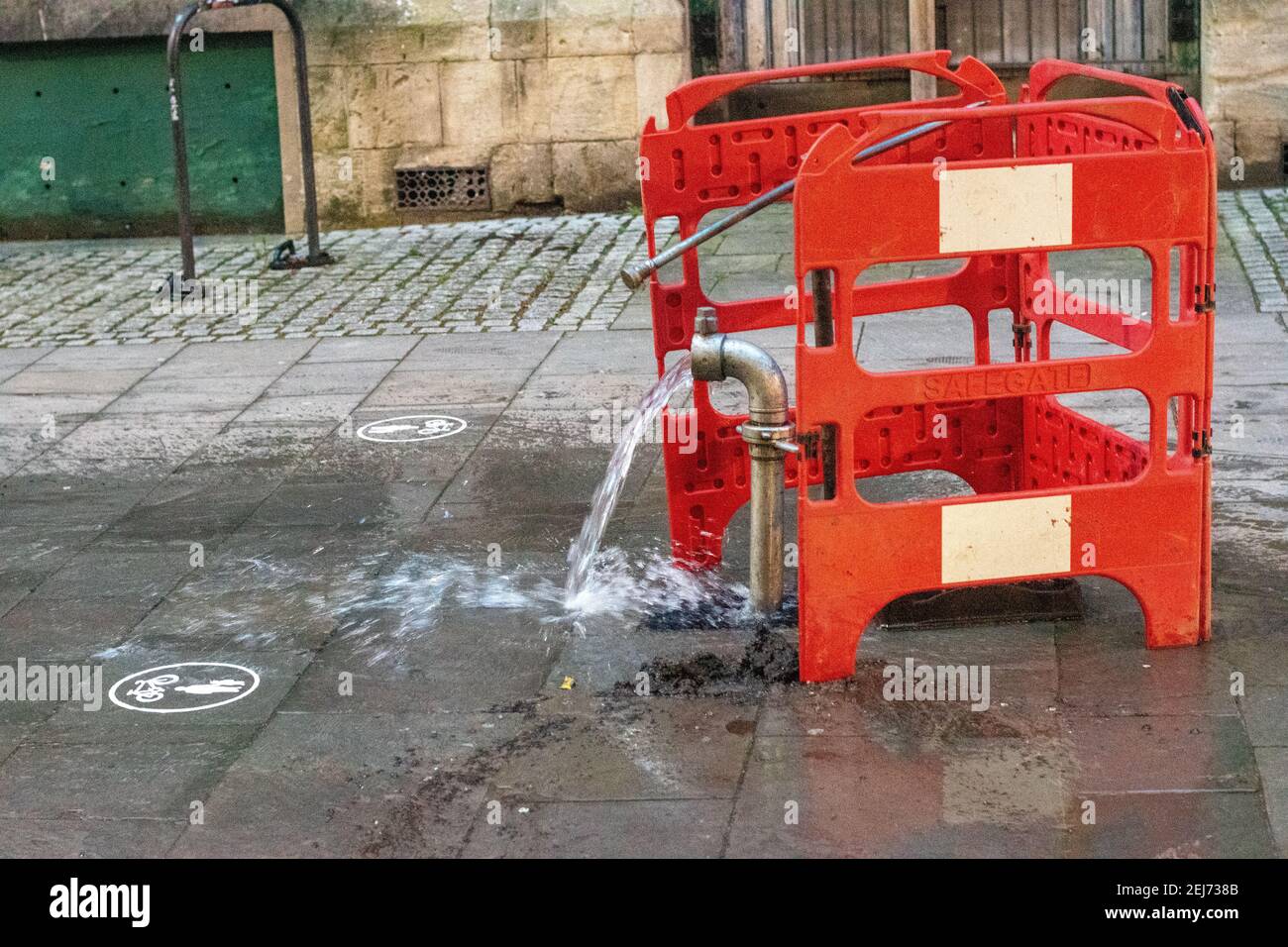 Burst acqua pipe in una strada urbana Foto Stock