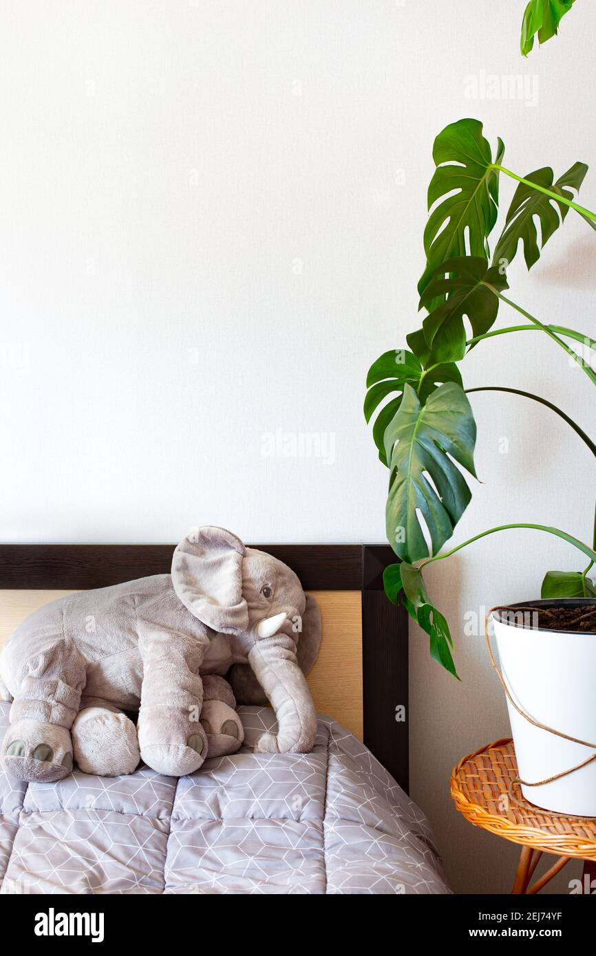 Camera da letto interna in stile scandinavo. Casa monstera, un elefante morbido giocattolo Foto Stock