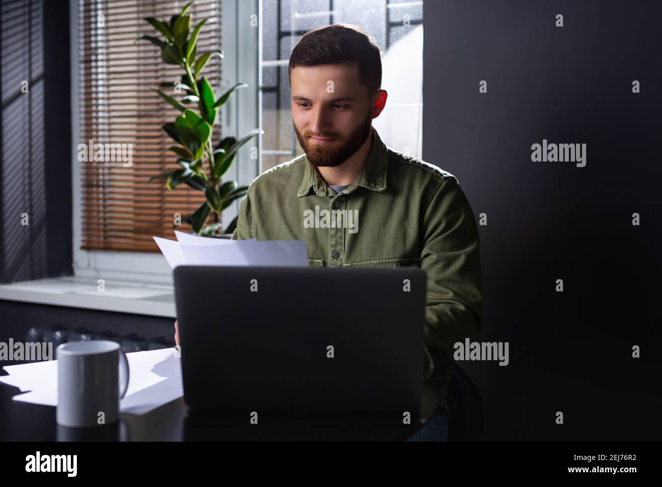 L'immagine di un giovane imprenditore o manager analizzando attentamente il tasso di aumento o di diminuzione dei profitti. Lavorare efficacemente da casa durante un Foto Stock