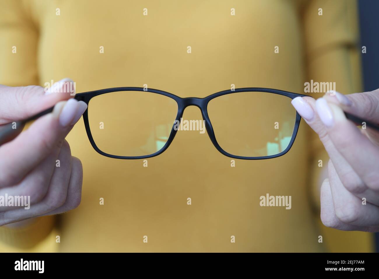 Donna che tiene gli occhiali neri nel suo closeup delle braccia Foto Stock