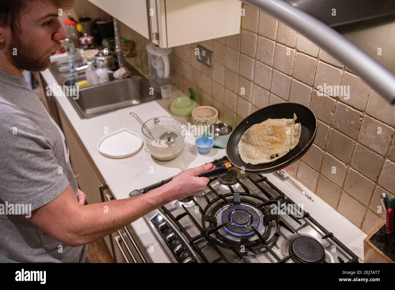 Un adolescente lancia una frittella il giorno della frittella, il martedì di Shrove Foto Stock