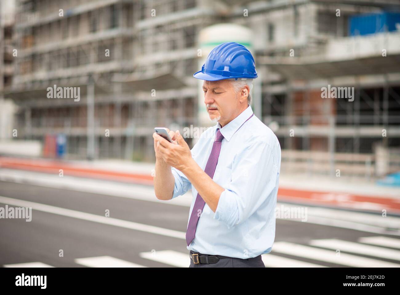 Architetto che utilizza il suo smartphone mobile di fronte a una costruzione sito Foto Stock