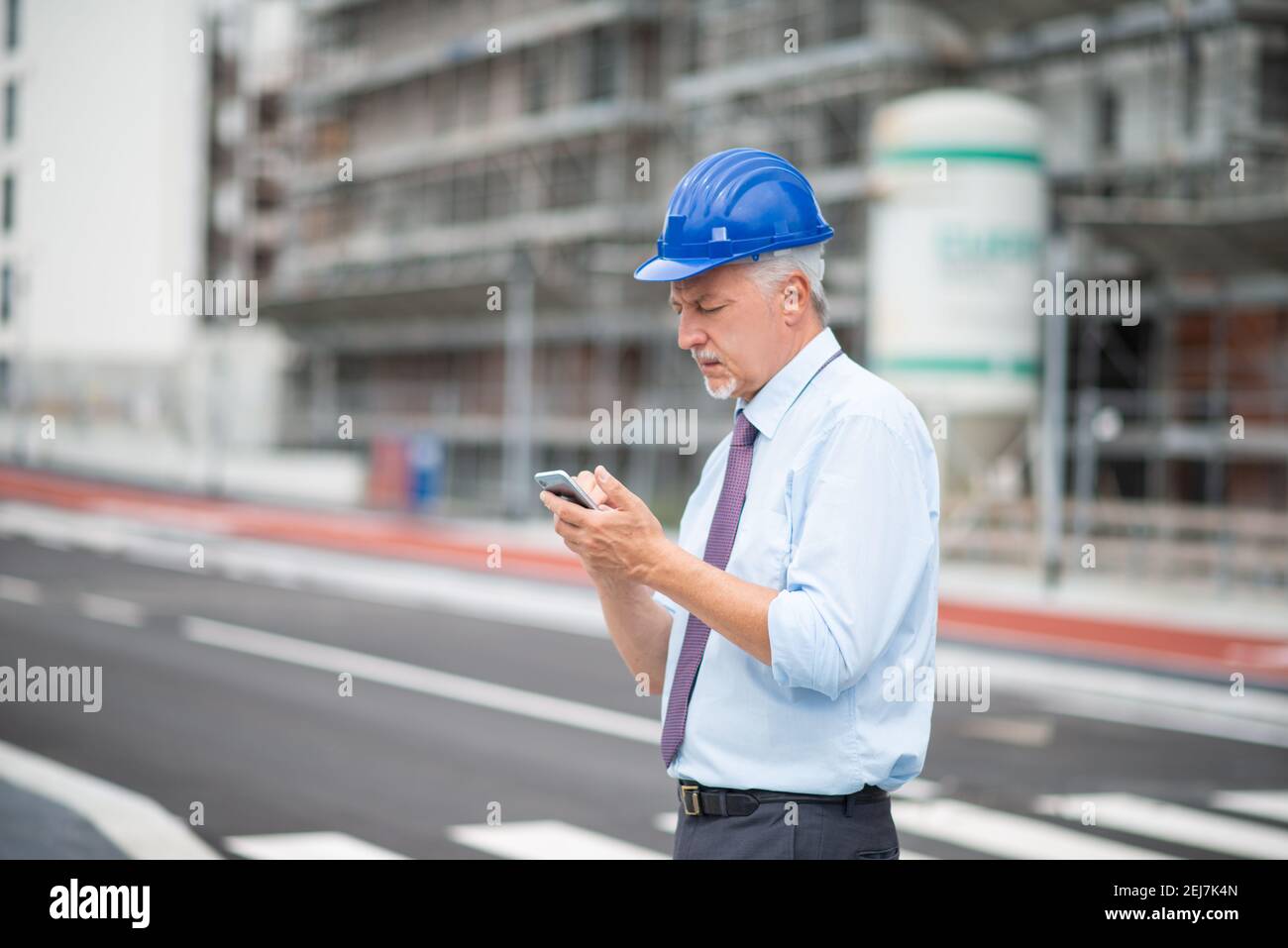 Architetto che utilizza il suo smartphone mobile di fronte a una costruzione sito Foto Stock