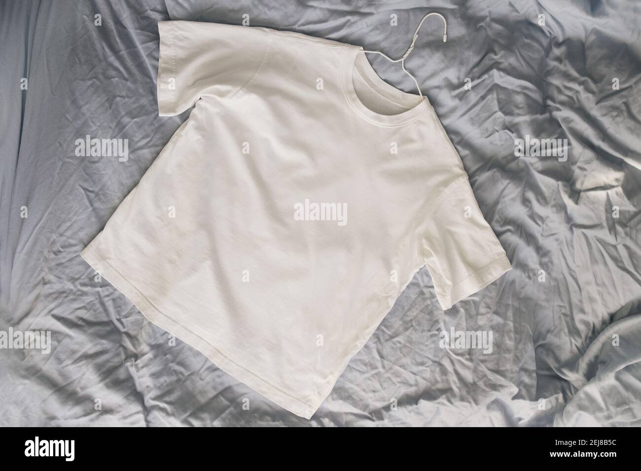 T-shirt in cotone bianco sul letto Foto Stock