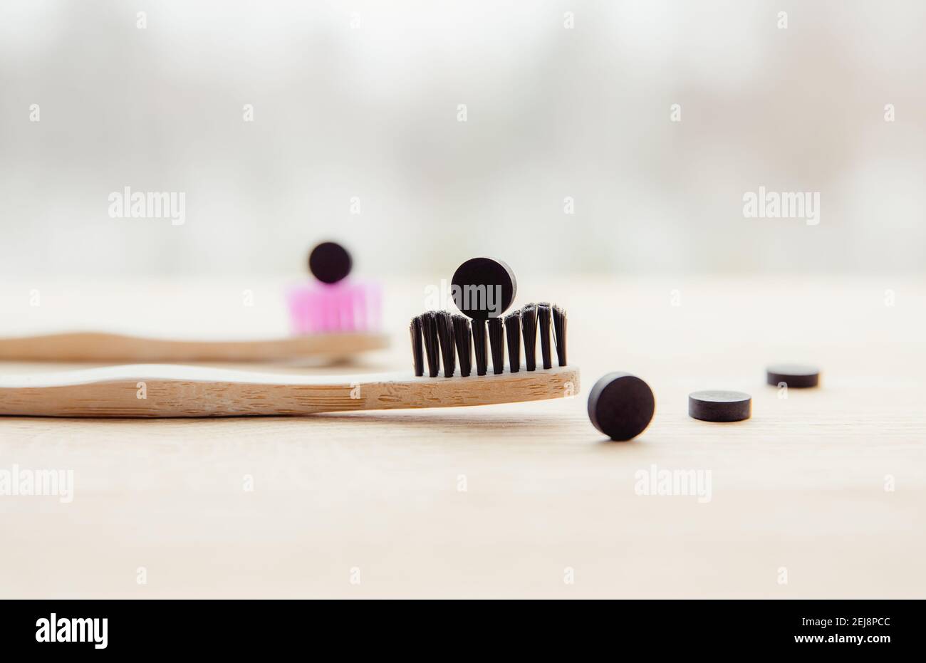 Vista laterale delle compresse di dentifricio nero a carbone attivo. Concetto di cura dentale. Ingredienti naturali, vista laterale dello spazzolino di bambù con nero. Foto Stock