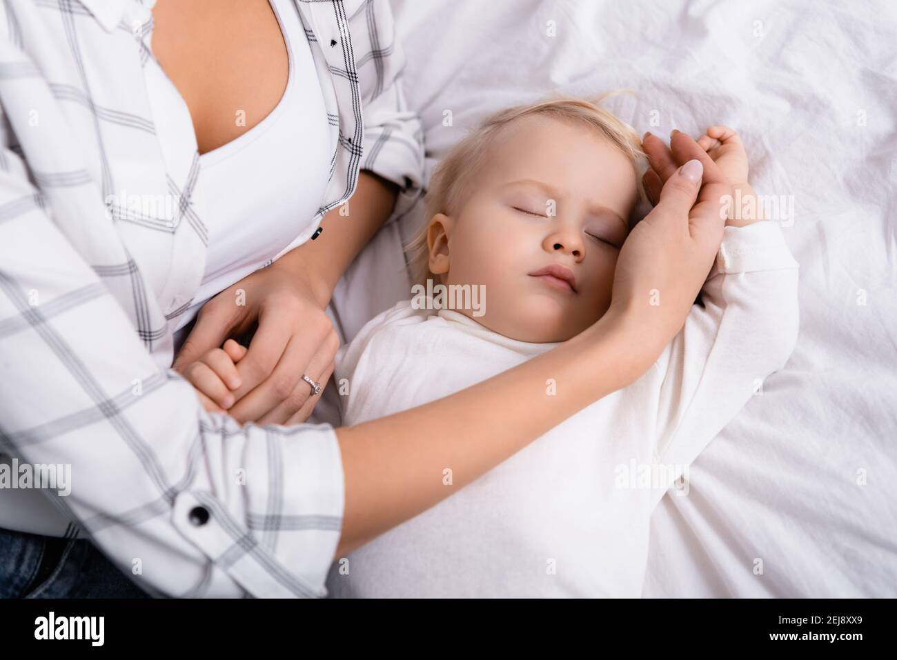 donna che tocca il figlio del bambino che dorme in camera da letto Foto Stock