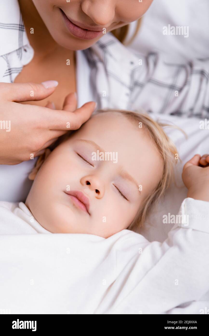 donna sorridente che tocca la testa del figlio del bambino addormentato Foto Stock