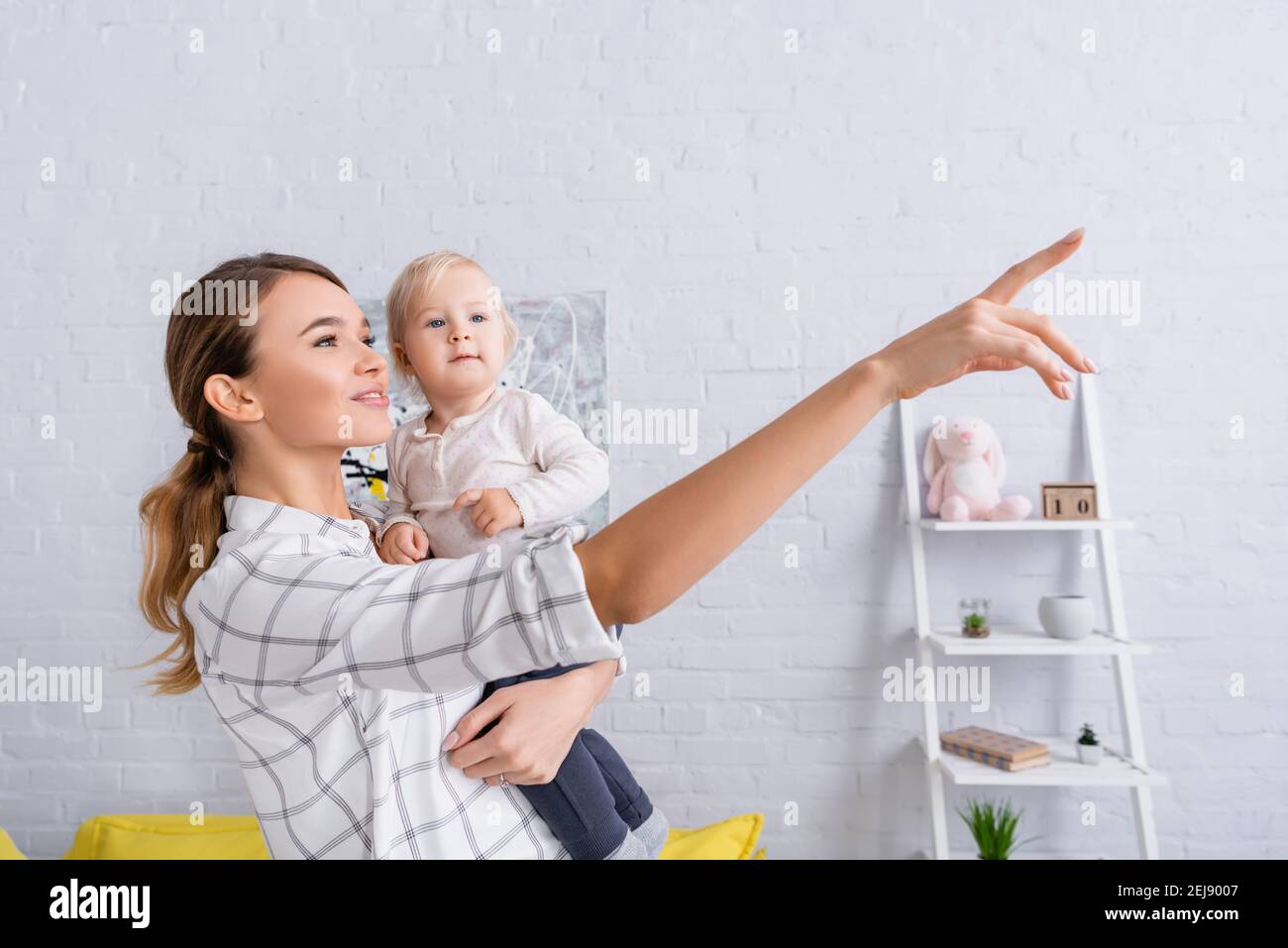 donna sorridente che punta con il dito mentre tiene il figlio del bambino Foto Stock