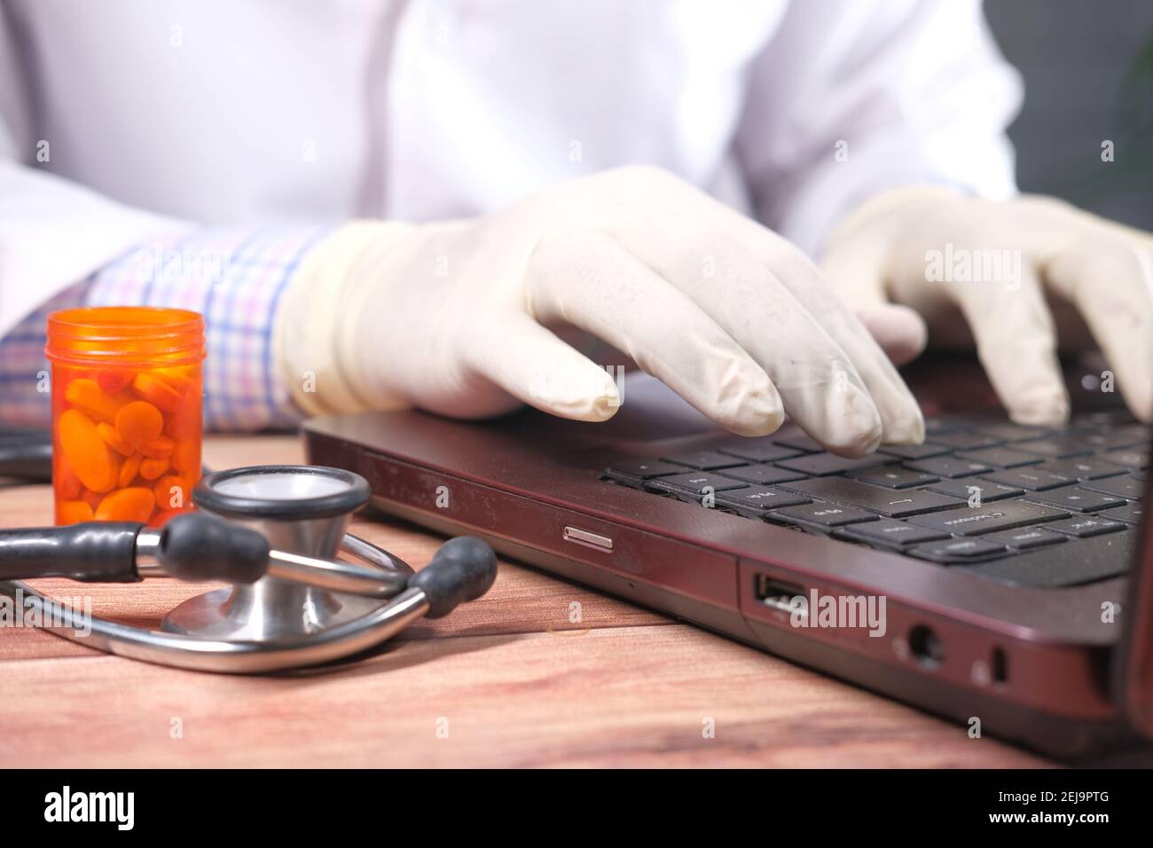 primo piano della mano del medico in guanti di lattice che digitano sopra computer portatile Foto Stock