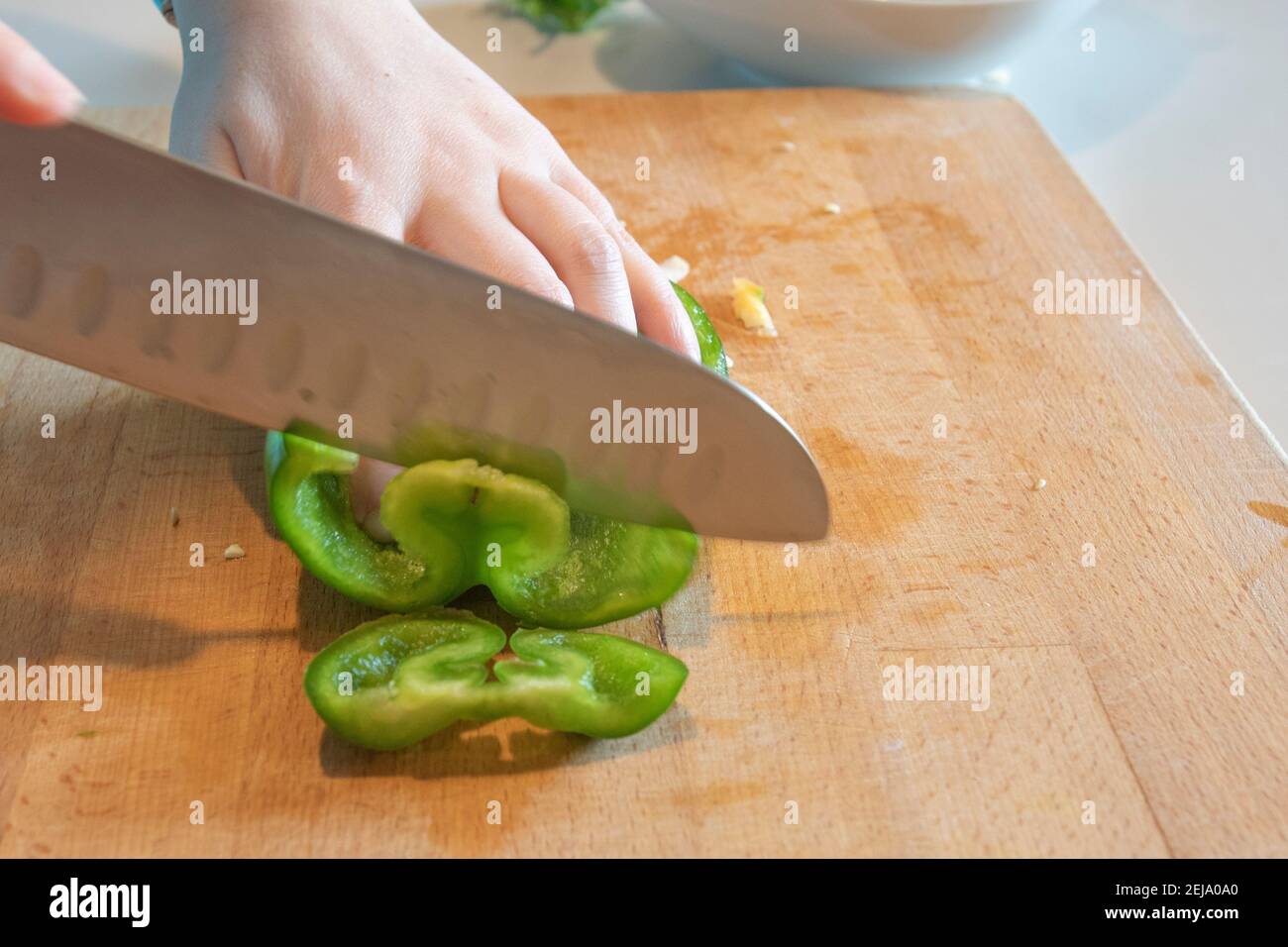 Mano femminile che affetta un peperone verde Foto Stock