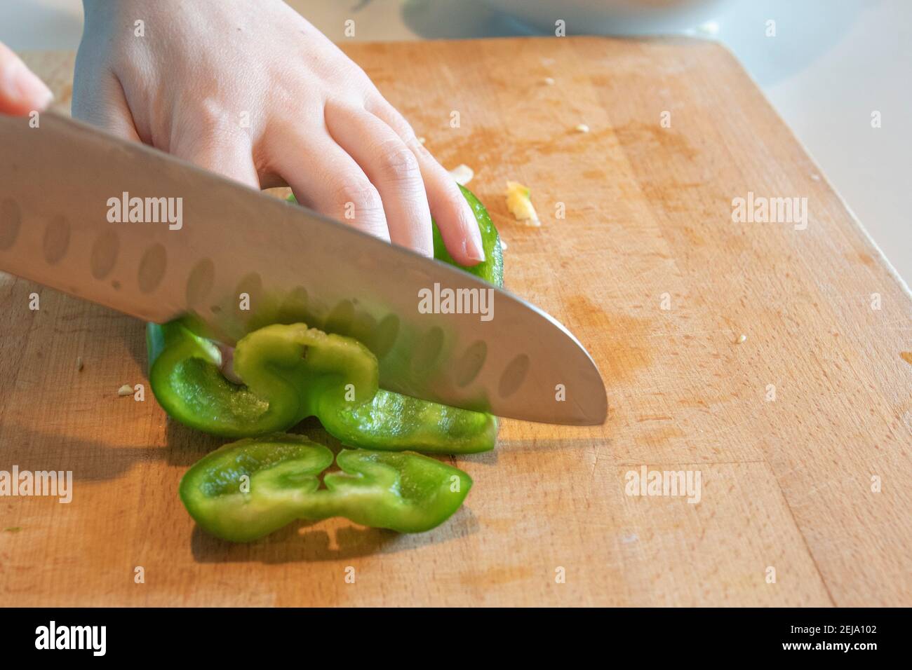 Mano femminile che affetta un peperone verde Foto Stock