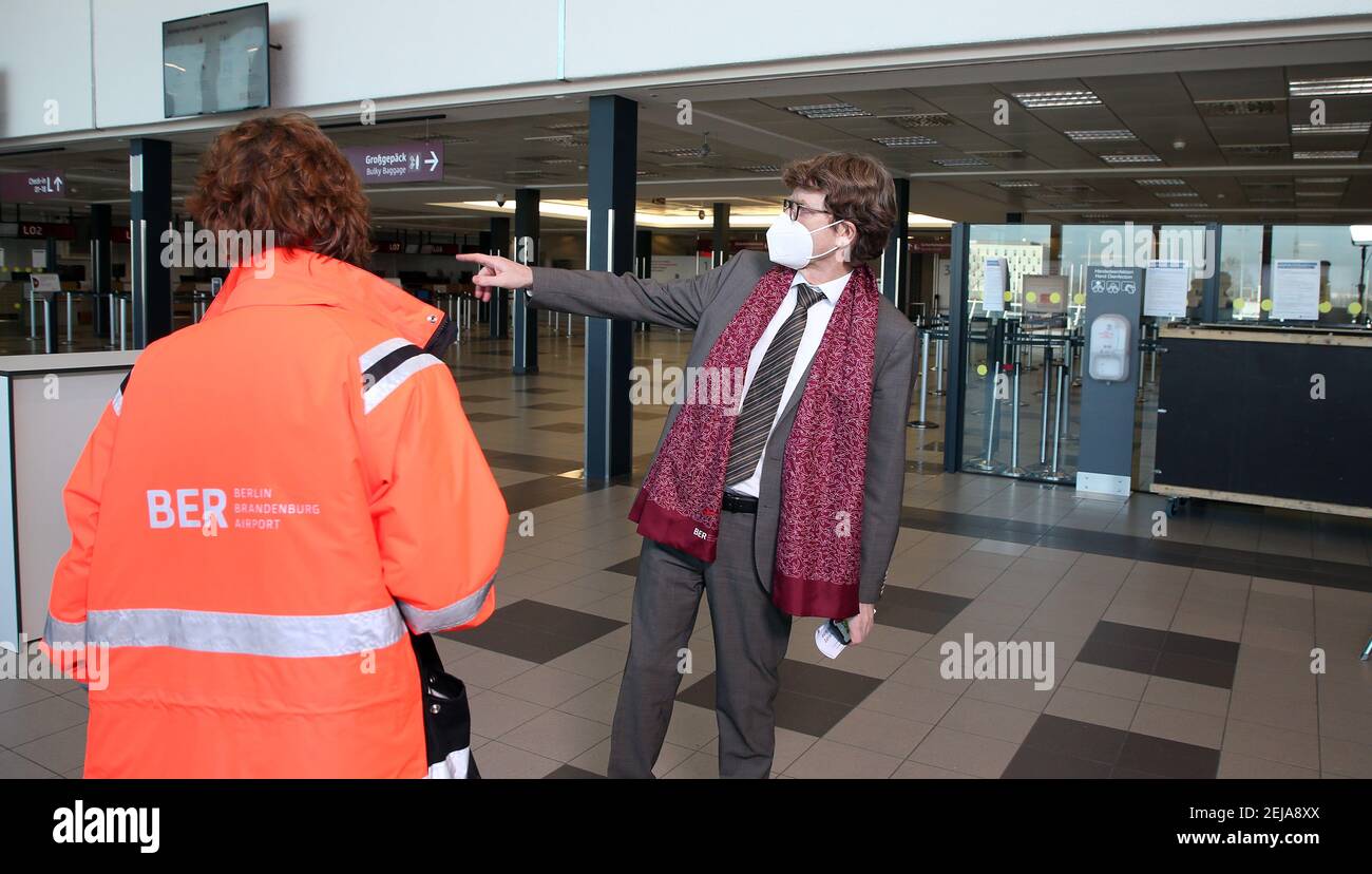 Berlino, Germania. 22 Feb 2021. Engelbert Lütke Daldrup, capo dell'aeroporto, e un dipendente dell'aeroporto camminano attraverso la sala di check-in deserta su quello che è provvisoriamente l'ultimo giorno di operazioni al Terminal 5 dell'aeroporto della capitale BER. A seguito della crisi dei numeri dei passeggeri, il vecchio terminale sarà inizialmente portato fuori linea per un anno per motivi di costo. Le operazioni di BER saranno quindi eseguite esclusivamente attraverso il nuovo terminal 1. Foto: Wolfgang Kumm/dpa Credit: dpa Picture Alliance/Alamy Live News Foto Stock