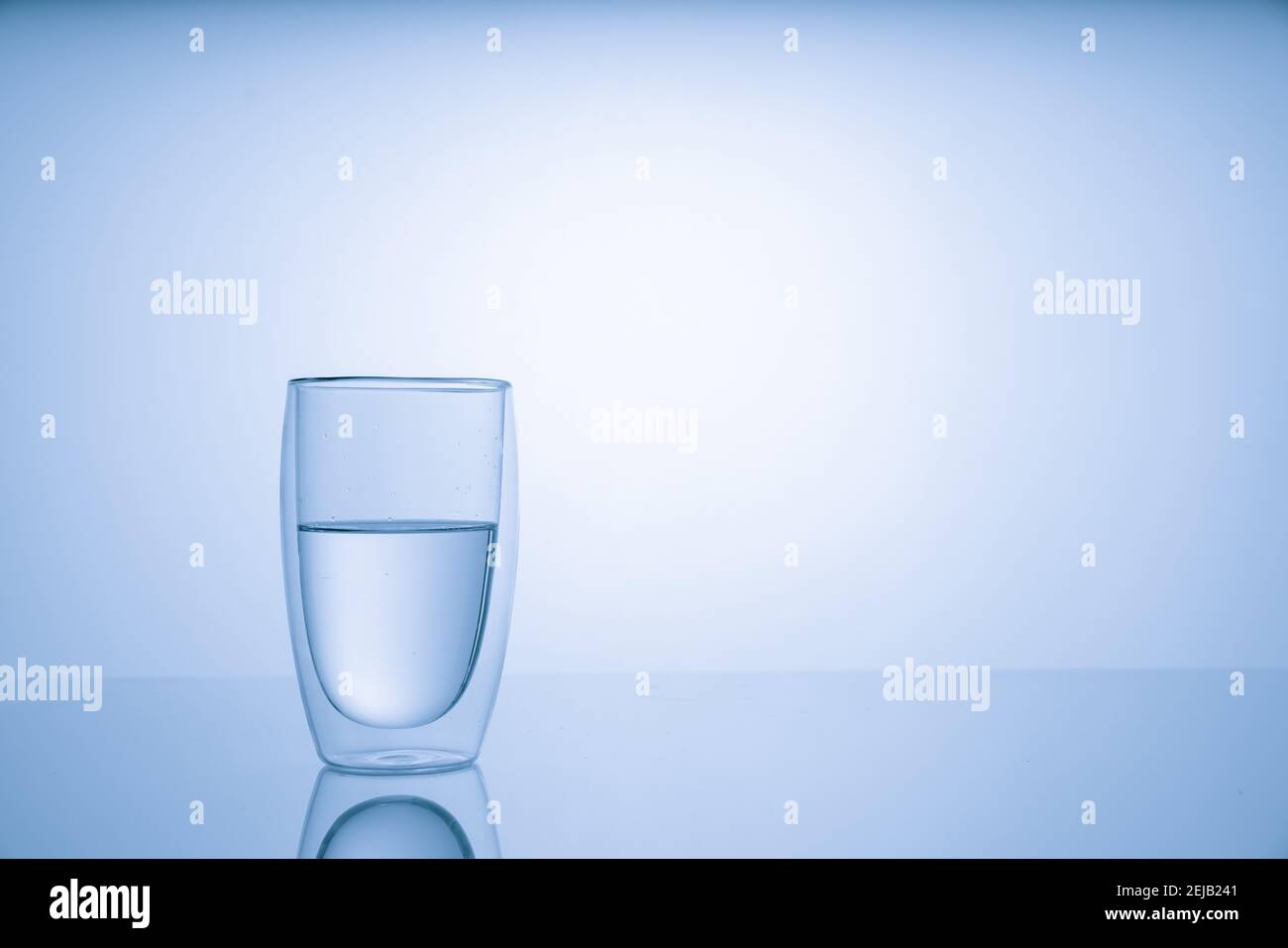 Caraffa con acqua potabile e un bicchiere con una bevanda, tonalità blu Foto Stock
