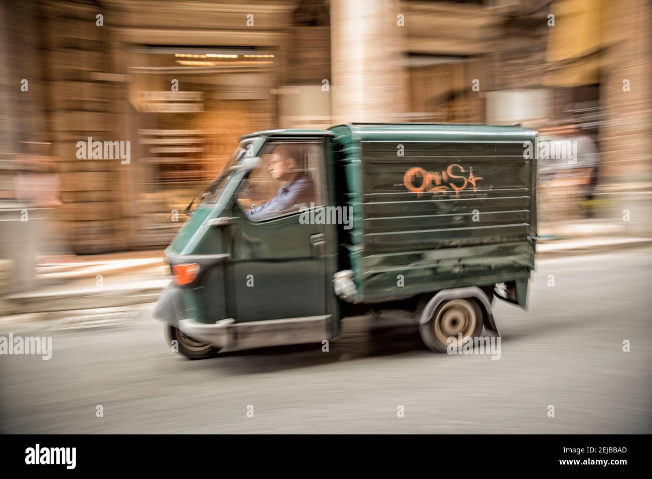Un furgone a tre ruote Piaggio guidato per le strade di Bologna Italia mostrando velocità con sfocatura del movimento, Foto Stock
