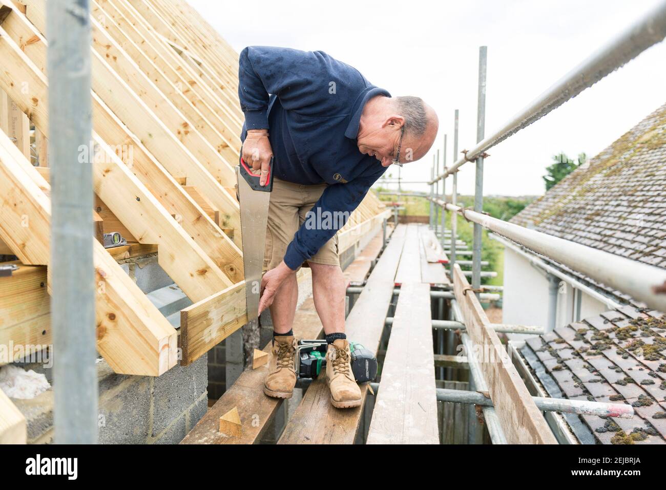 Operai che costruiscono una stanza sul tetto di una proprietà residenziale che era un bungalow. Foto Stock