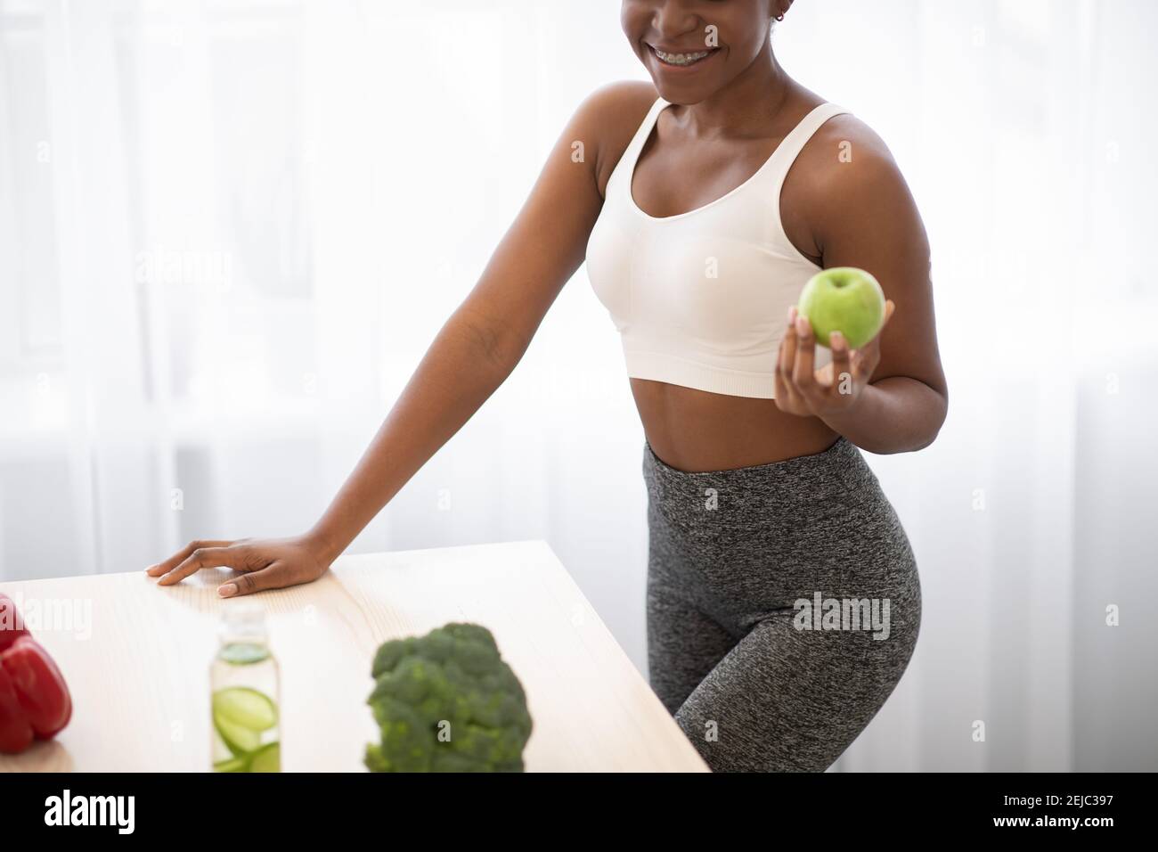 Irriconoscibile Donna nera che tiene Apple perdere peso in piedi in cucina Foto Stock