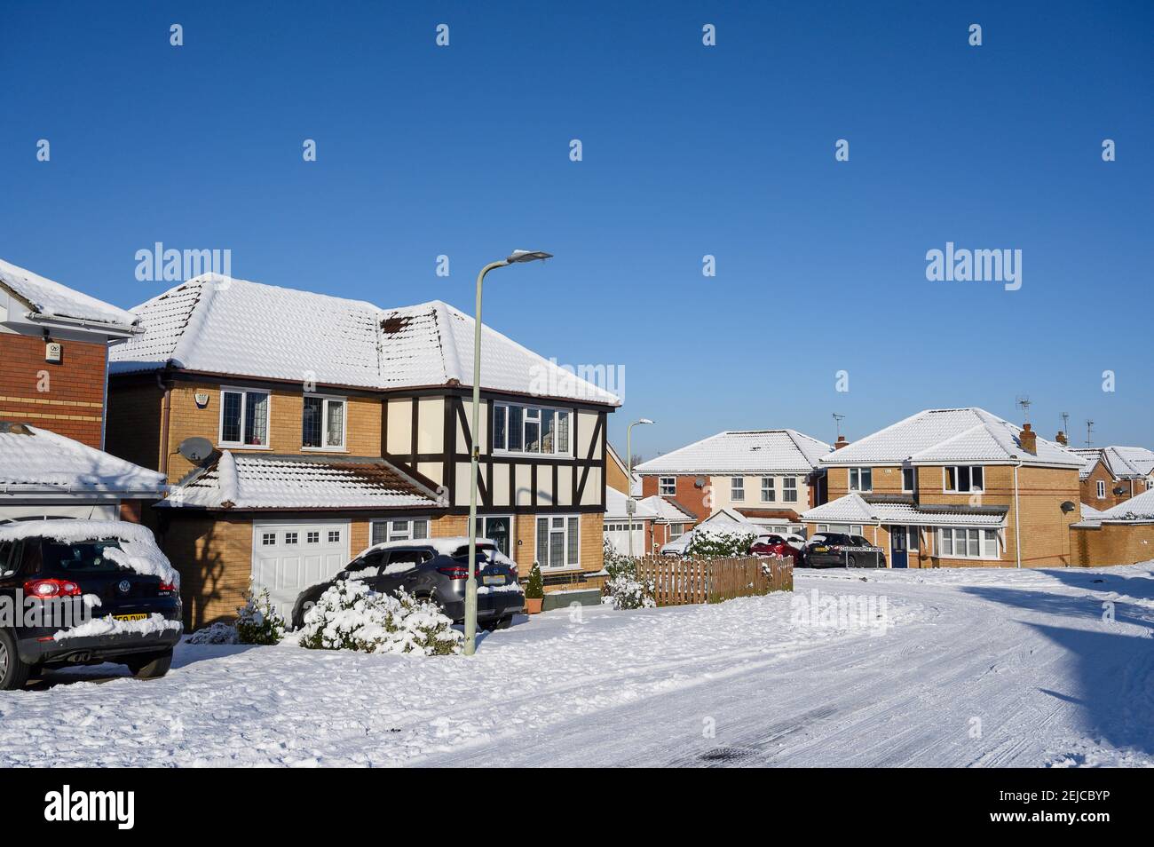 Strada coperta di neve in un giorno d'inverno in una tenuta di case a Market Harborough, Leicestershire, Regno Unito. Foto Stock