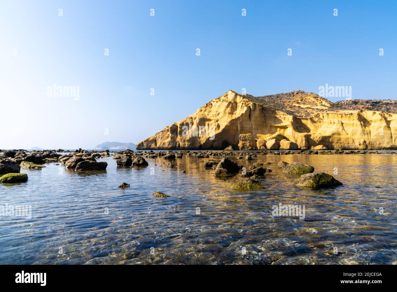 Vista della calma idilliaca acqua dell'oceano nel Mediterraneo con scogliere di arenaria gialla dietro Foto Stock