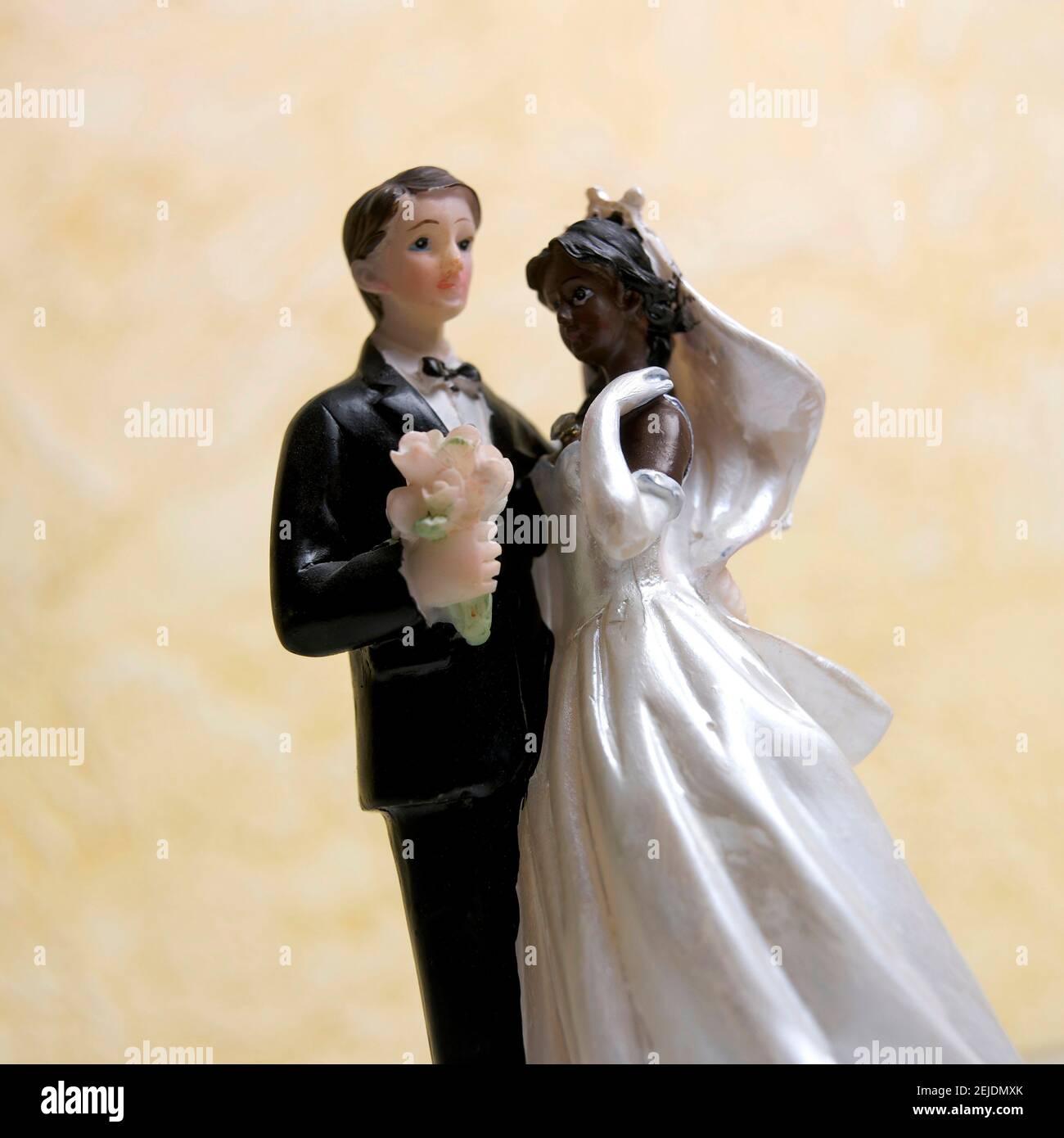 Torta nuziale con uno sposo in un smoking nero e una sposa in abito bianco con bouquet Foto Stock