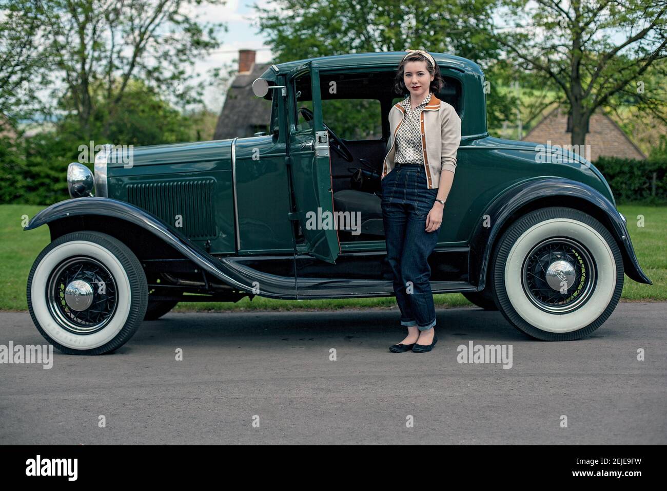 Giovane donna in piedi accanto a un'auto d'epoca. Foto Stock