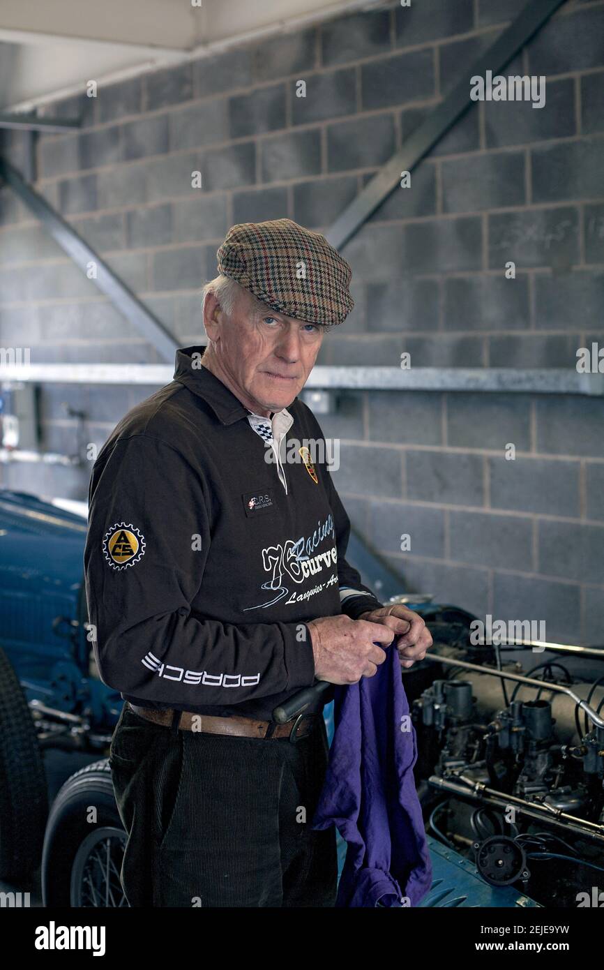 Un uomo anziano pulisce le mani dopo aver effettuato la manutenzione della sua auto d'epoca in garage. Foto Stock