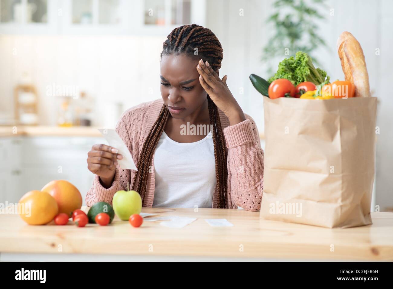 Spese alimentari. Preoccupatevi Black Lady controllare Bill in cucina dopo lo shopping alimentare Foto Stock