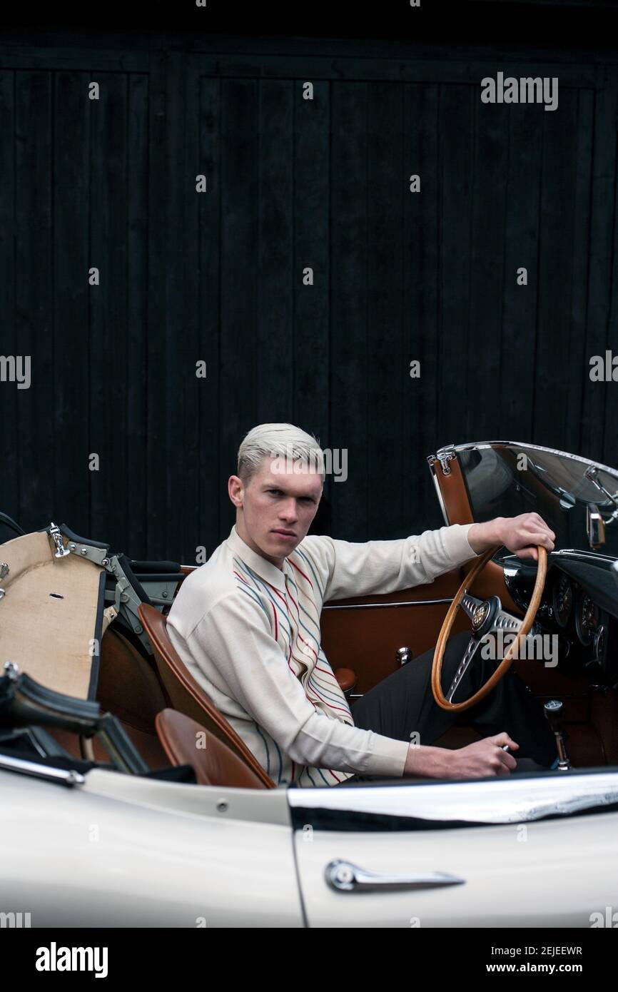 Elegante giovane uomo fuori su un viaggio con auto convertibile classica guardando nella macchina fotografica , Inghilterra . Foto Stock