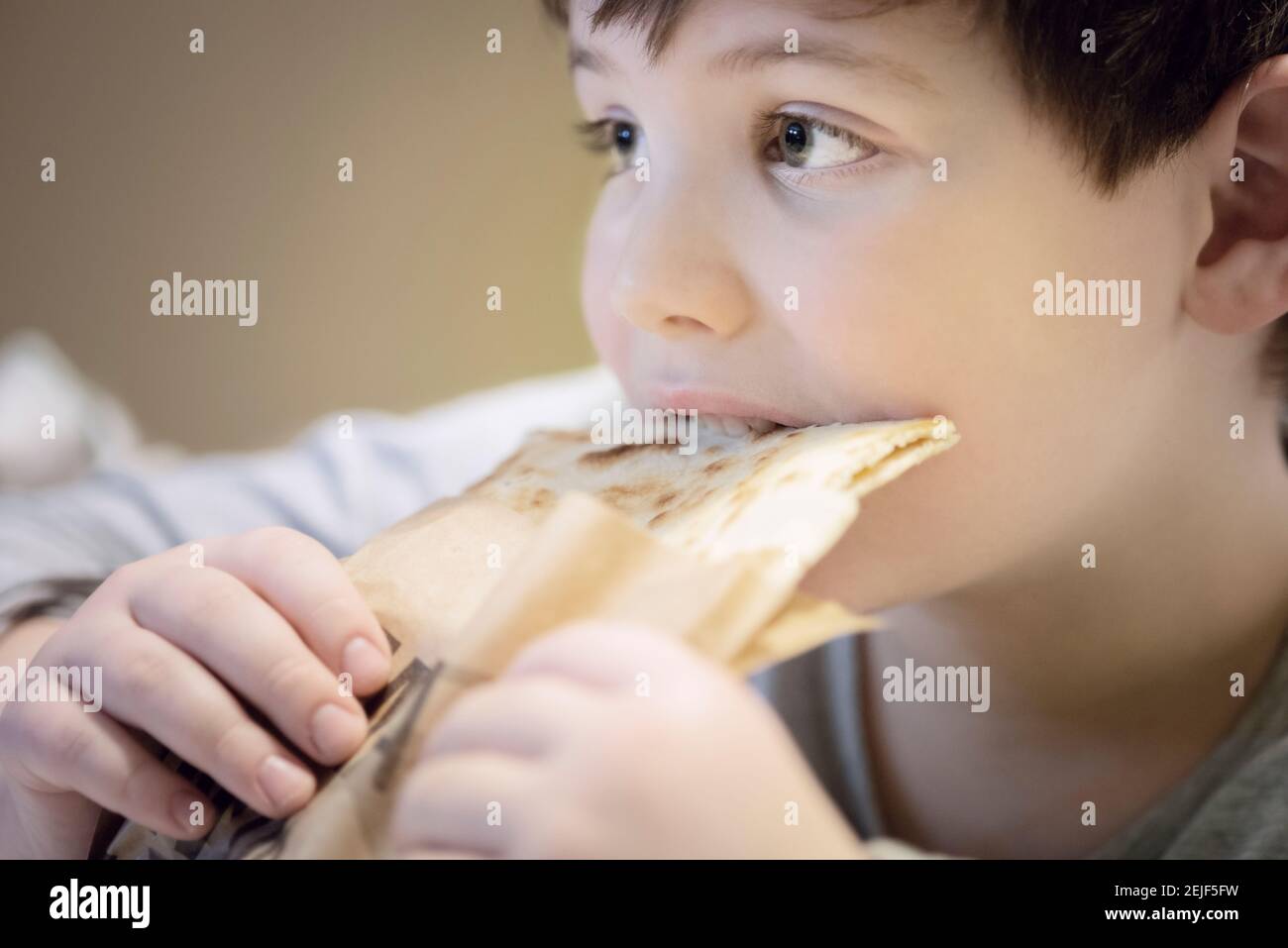Ragazzo che mangia Piadina mentre guardi la TV a casa Foto Stock