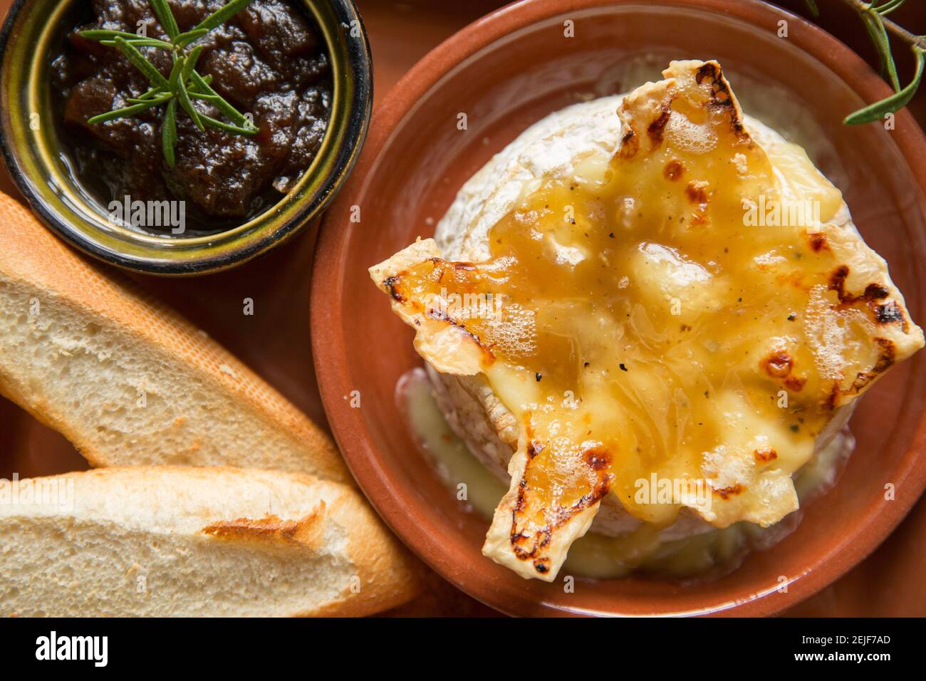 Camembert francese che è stato cotto in forno con tartufo, aglio e salsa al miele, servito con pane francese tostato e chutney di cipolla caramellata Foto Stock