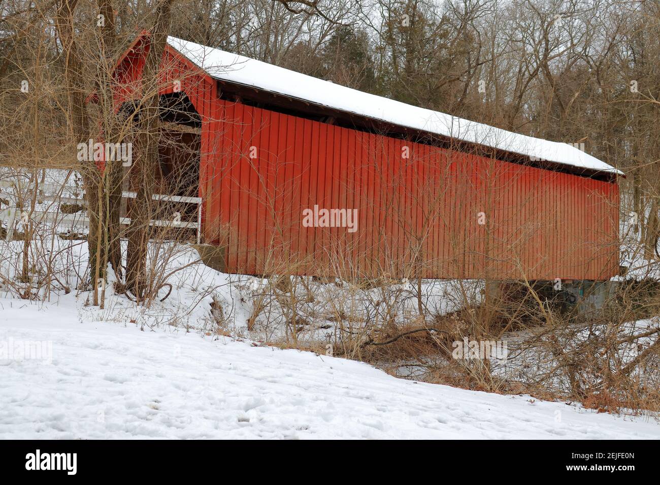 Un ponte rustico, rosso, coperto in una giornata invernale Foto Stock