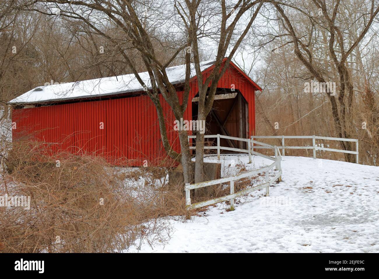 Un ponte rustico, rosso, coperto in una giornata invernale Foto Stock
