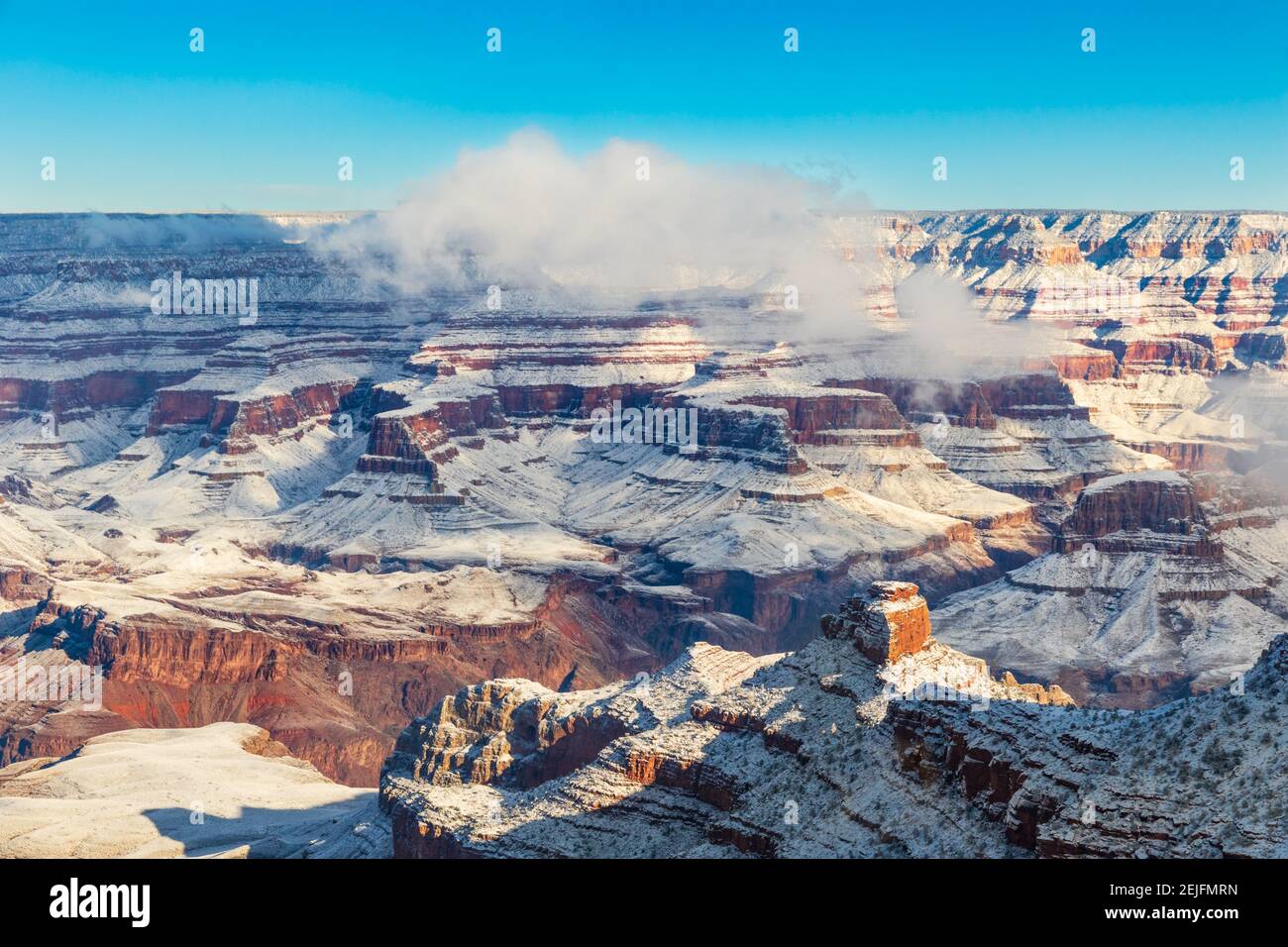 Grand Canyon al mattino, coperto di neve. Cielo blu; nuvole sul bordo del canyon. Foto Stock