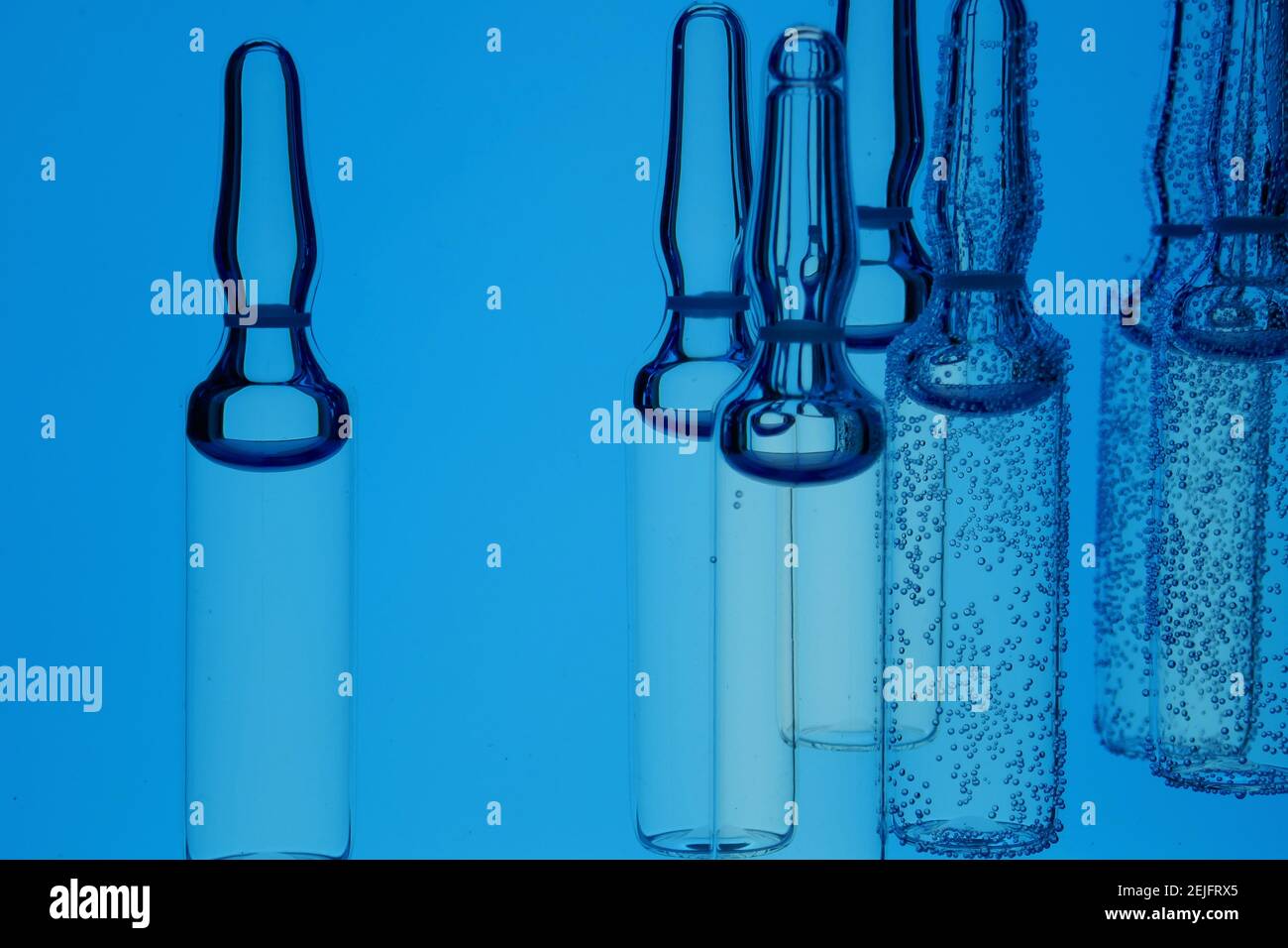 Fiale mediche.vaccino e siero .acido ialuronico.Medicina e bellezza. Ampolle in bolle d'aria in acqua blu.idratazione della pelle e trattamenti di bellezza Foto Stock