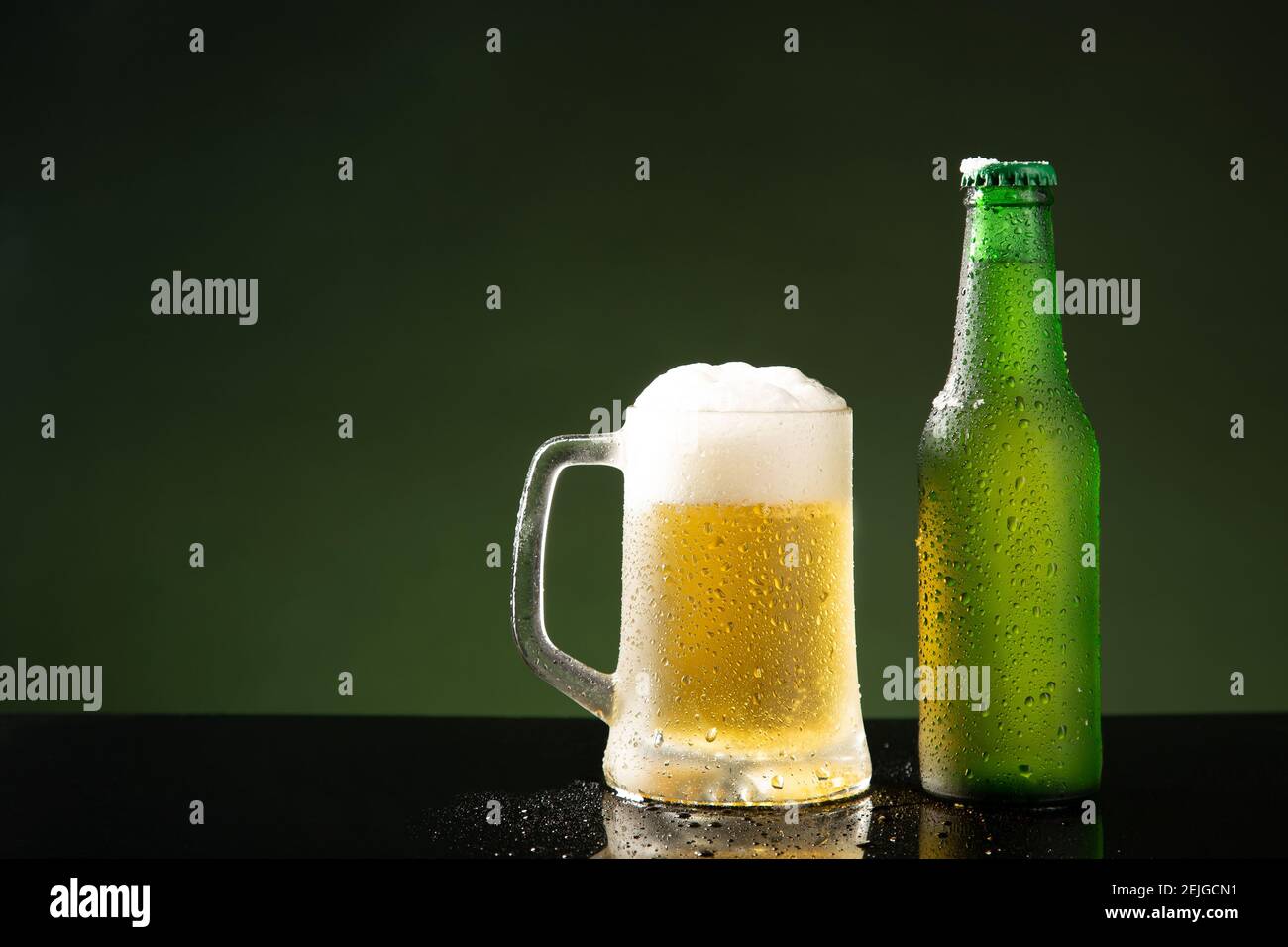 Tazza di birra e bottiglia su sfondo verde con copyspace. Foto Stock