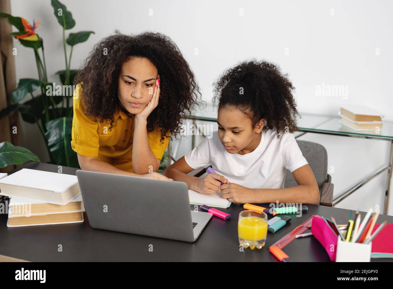 Madre afroamericana che aiuta la figlia a fare i compiti. Concetto di scuola domestica. Foto Stock