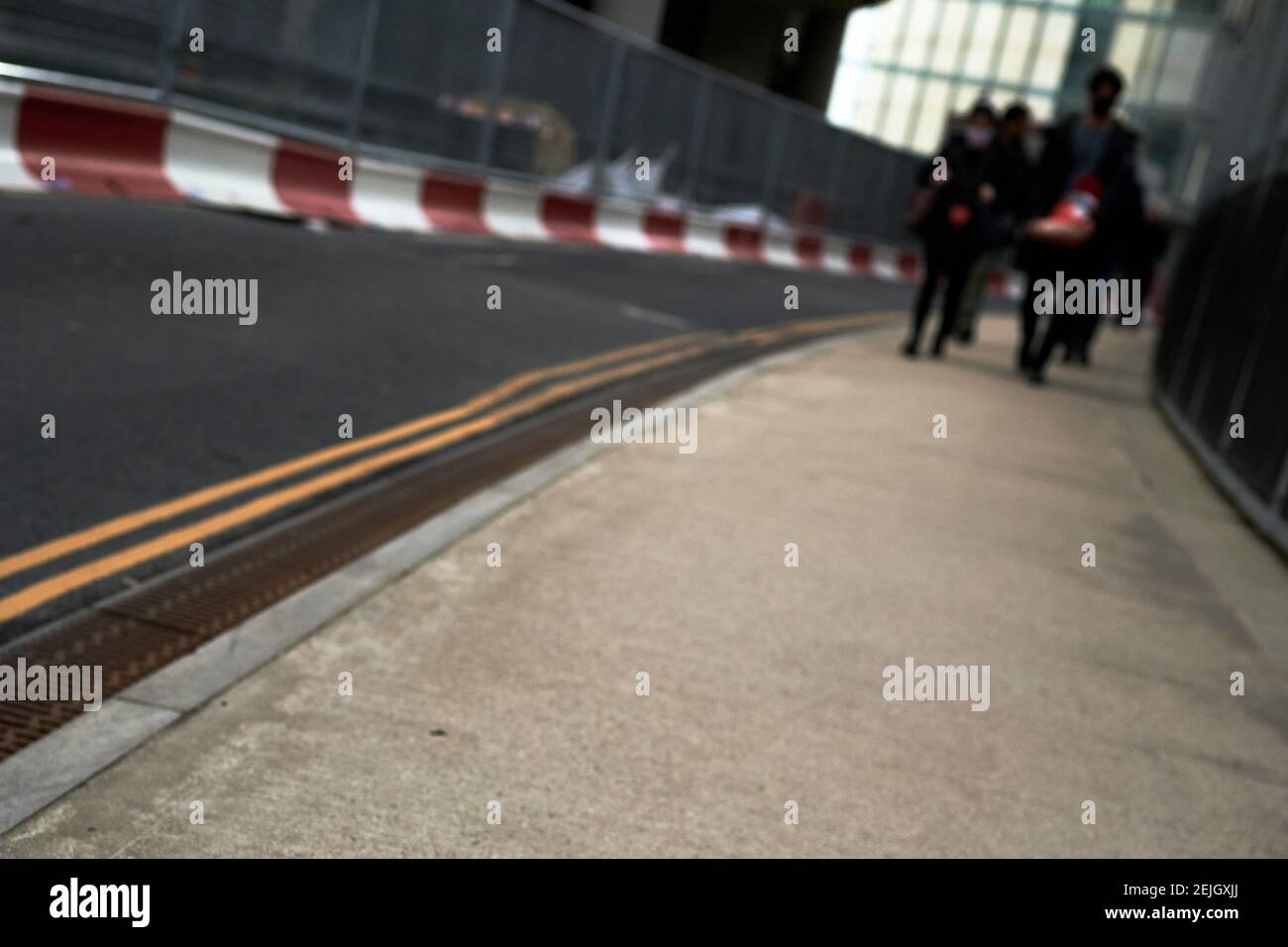 Vista sfuocata dei pedoni sulla strada con doppia linee in strada e lavori di costruzione in background durante il giorno Foto Stock