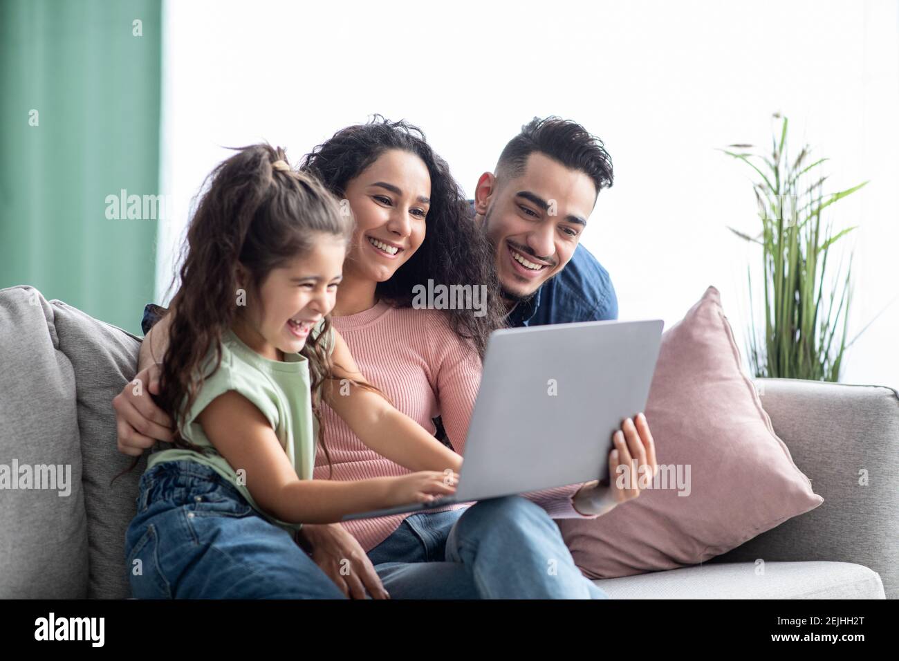 Allegra famiglia arabica che si diverte con il computer portatile a casa, guardando le foto insieme Foto Stock