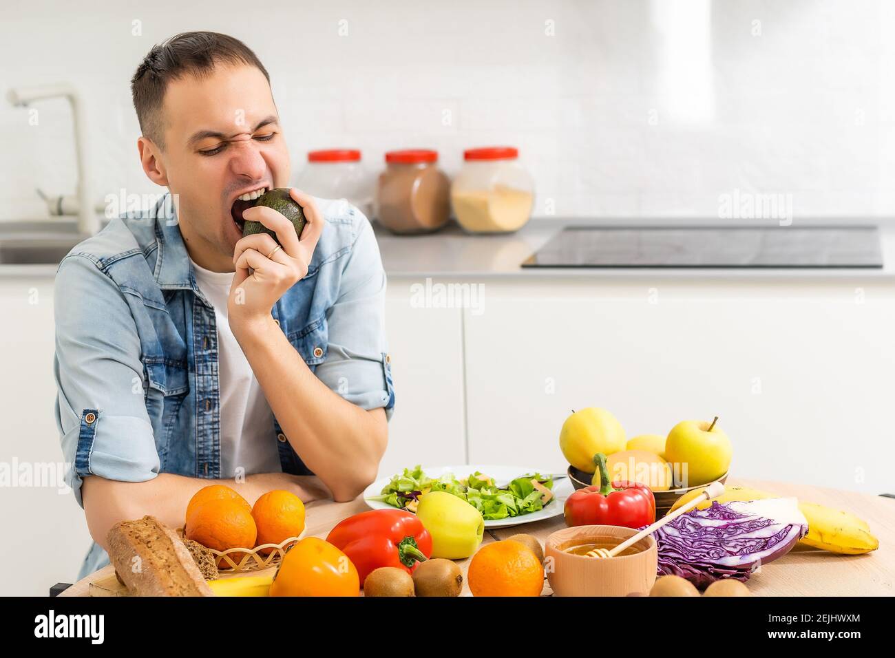Felice giovane uomo preparare una cena romantica alla ricerca di ricette vegetali menù dieta, sorridente marito cucina sano vegan cibo tagliato insalata in cucina Foto Stock
