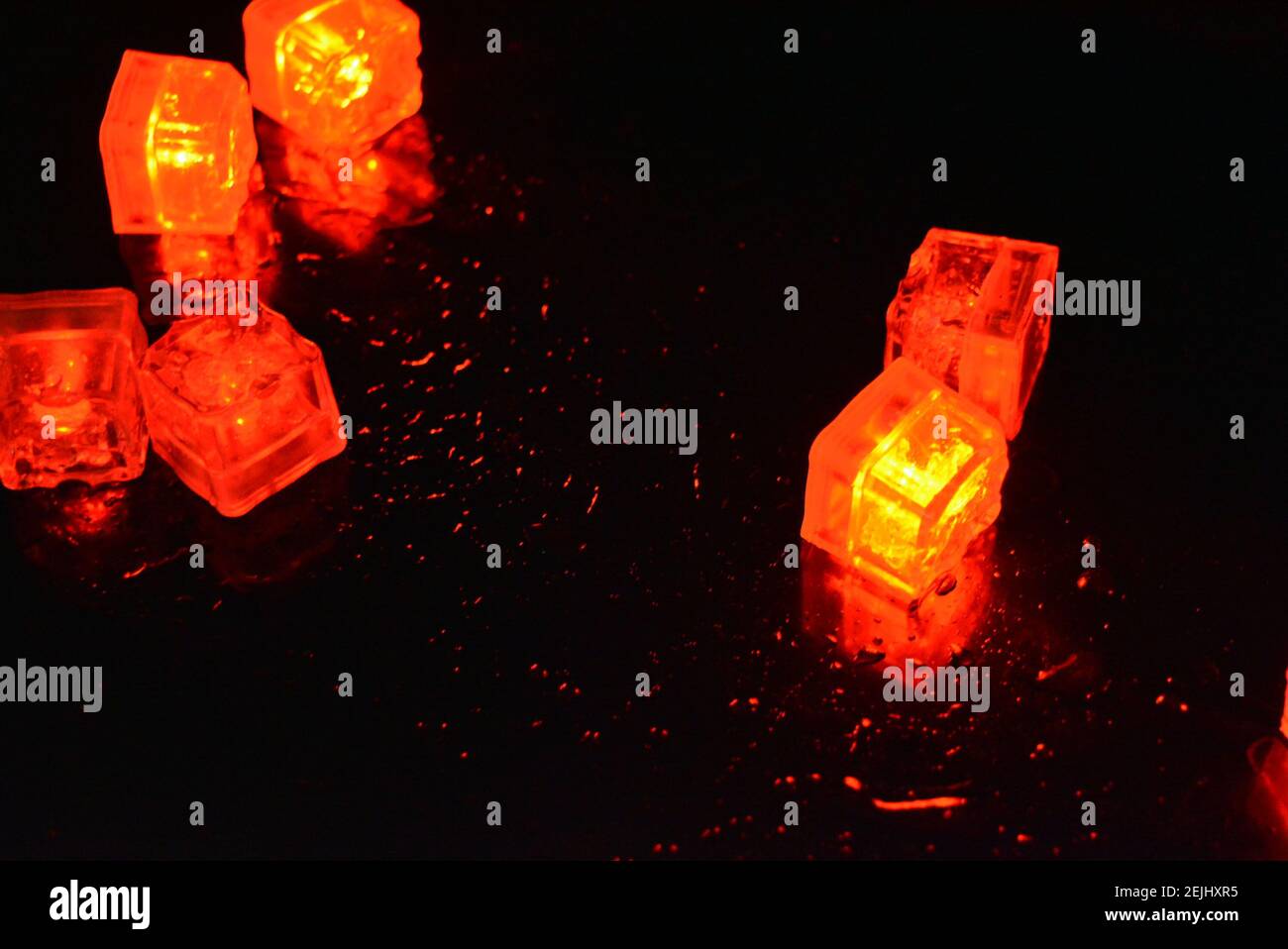 Molto luminoso e non normale sfondo di cubetti di ghiaccio rossi brillanti. Splendida illuminazione dalle mille sfaccettature con una luce speciale. Foto Stock