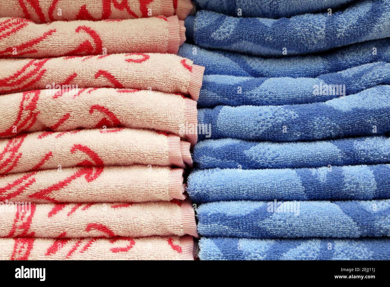 Una pila di asciugamani colorati in spugna. Fondo morbido, tessuto da bagno rosa e blu primo piano Foto Stock