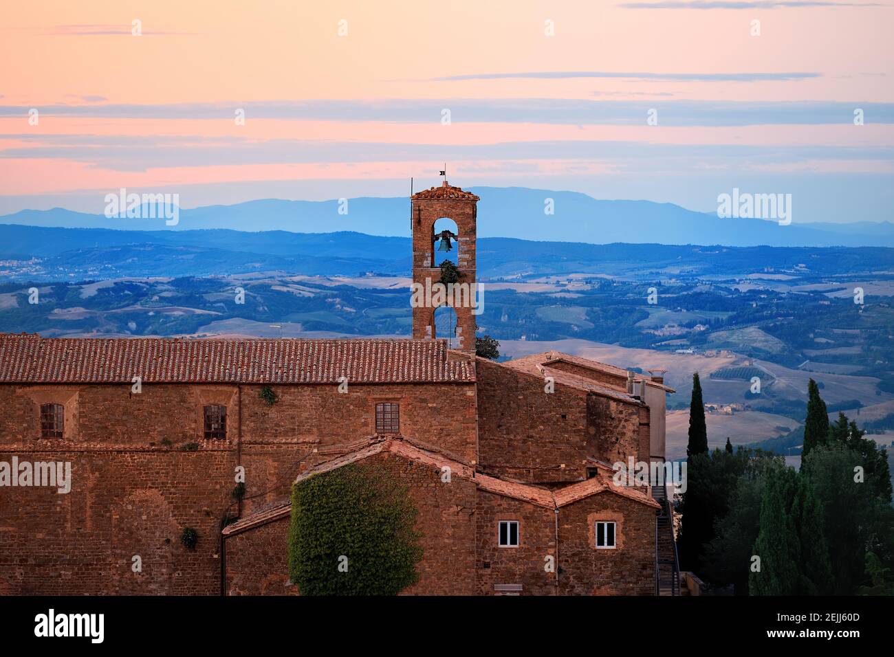 Antica città italiana Montalcino illuminata dal sole del mattino, panorama, vista su vigneti e ulivi. Toscana, Italia. Foto Stock