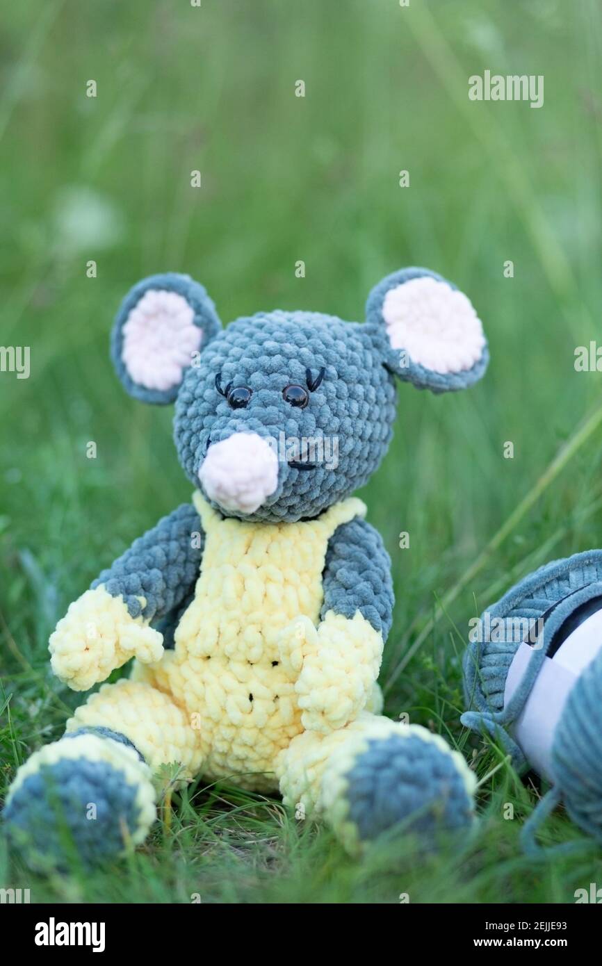 Giocattolo lavorato a maglia fatto a mano. Mouse lavorato a maglia in tute gialle sull'erba con posto per il tuo testo Foto Stock