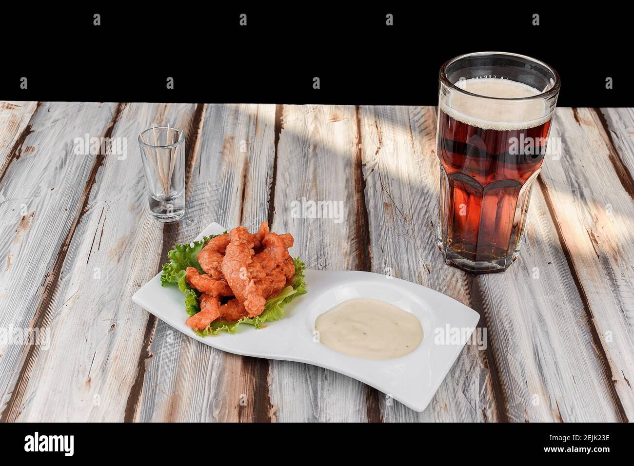 Piatto con ali di pollo con salsa rossa accompagnata da un birra scura Foto Stock