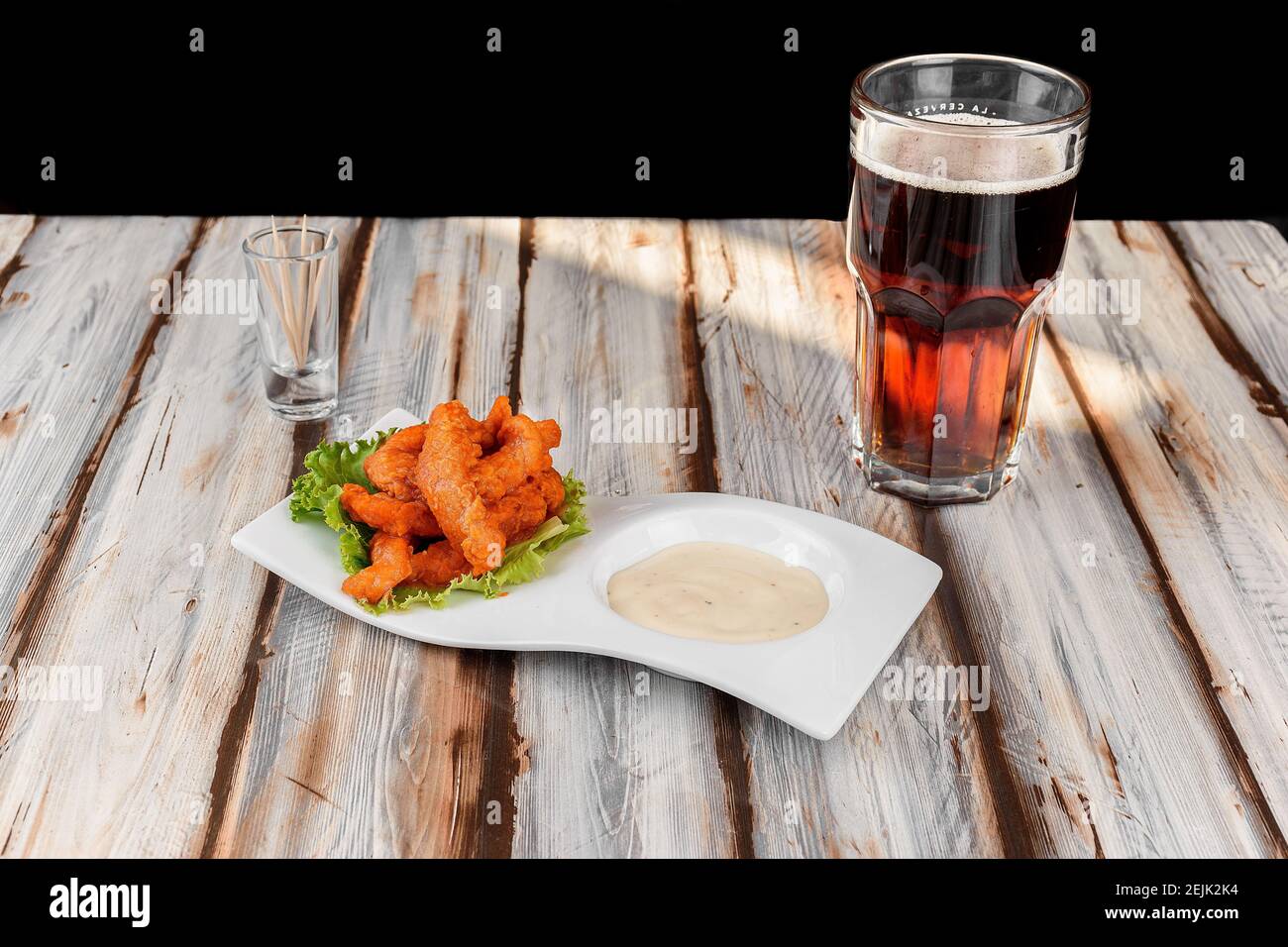 Piatto con ali di pollo con salsa rossa accompagnata da un birra scura Foto Stock